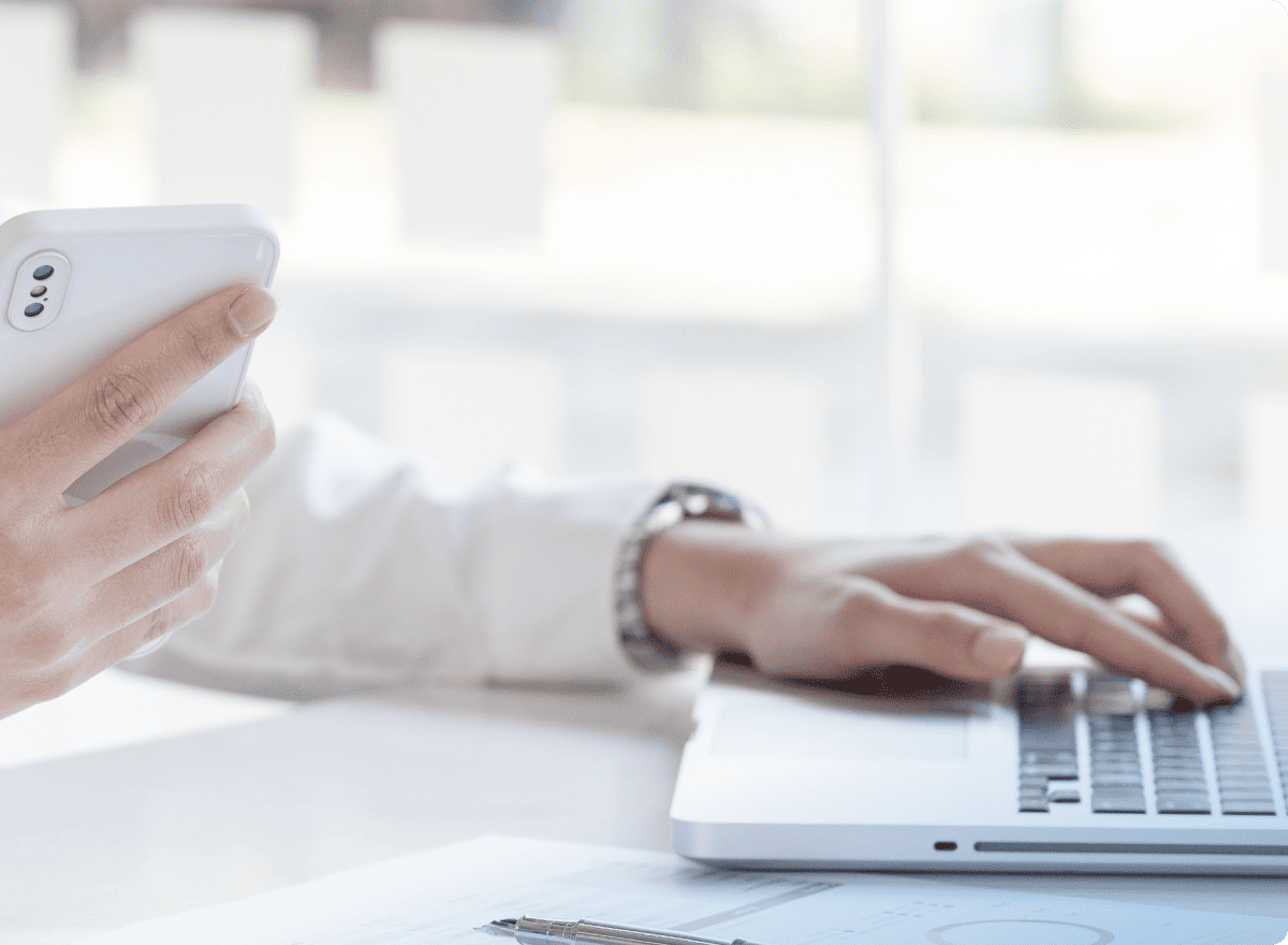 スマホを片手にパソコンを操作する人の手元